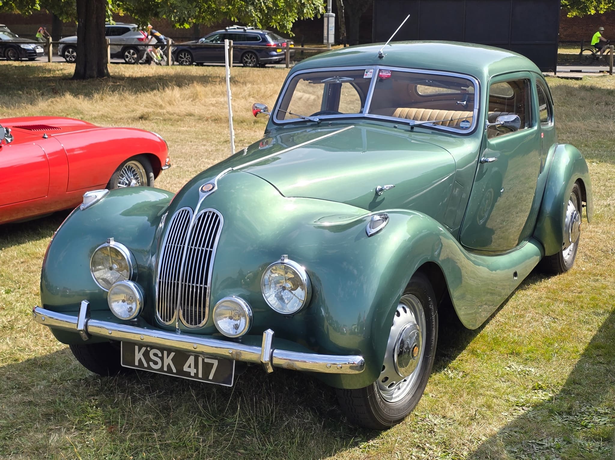 A green Bristol 400 saloon with a tall BMW-style twin grille parked on dry grass at a car show.