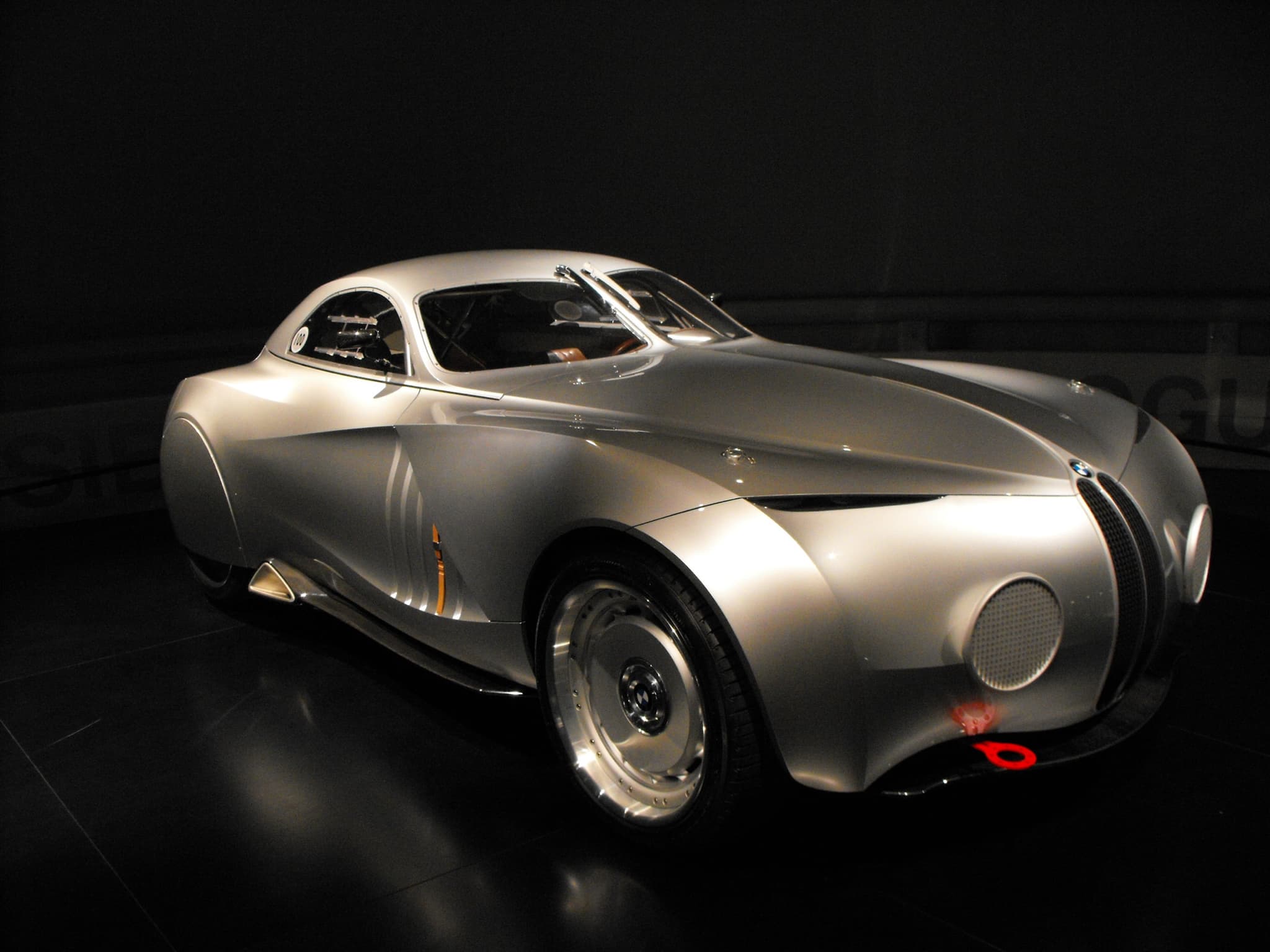 BMW's silver 2006 Concept Coupé Mille Miglia, a concept car, spot-lit in a dark museum space. Opens a larger view