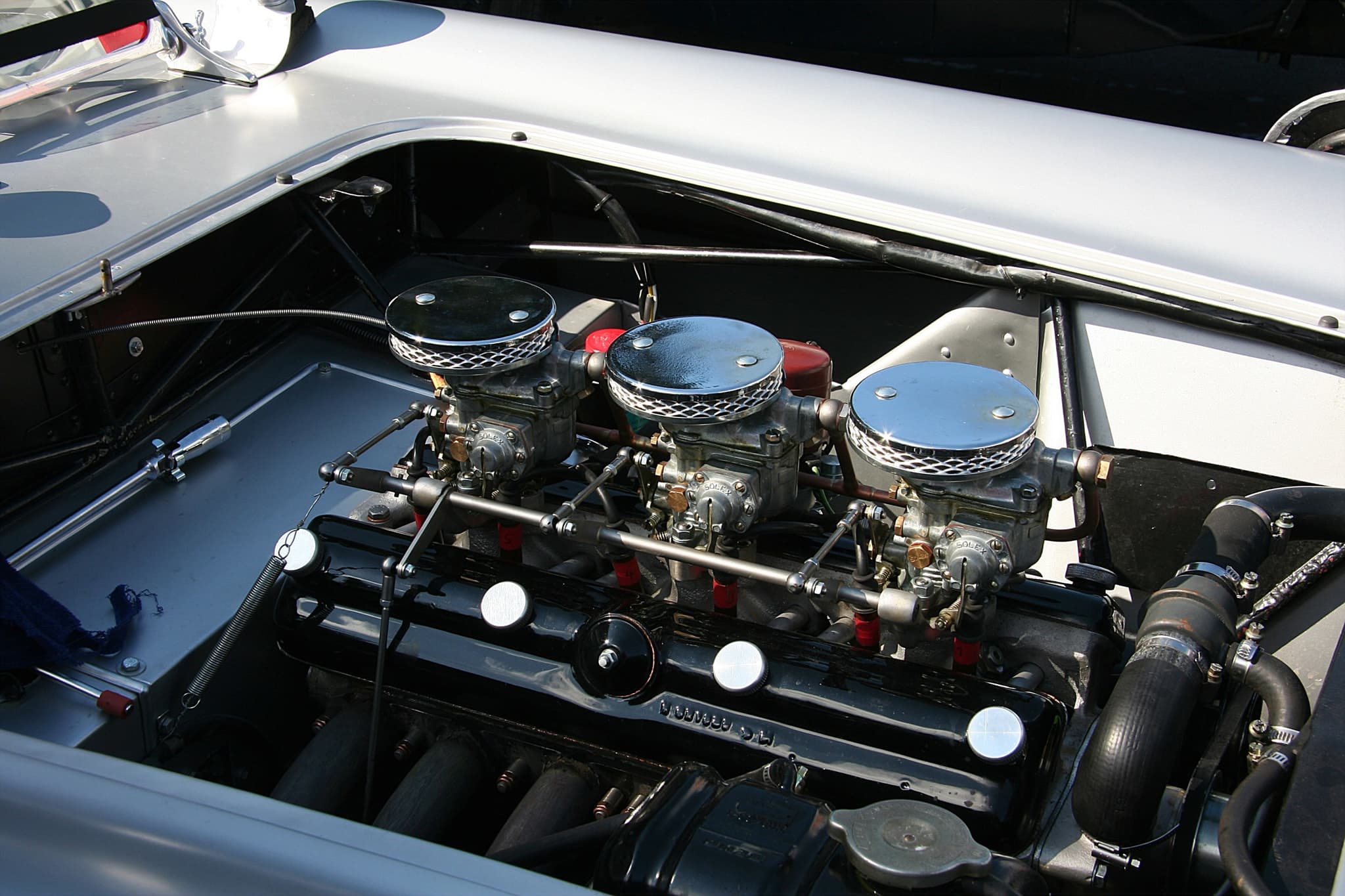 The engine bay of a silver Veritas racing car: a six-cylinder engine with three Solex downdraught carburettors.