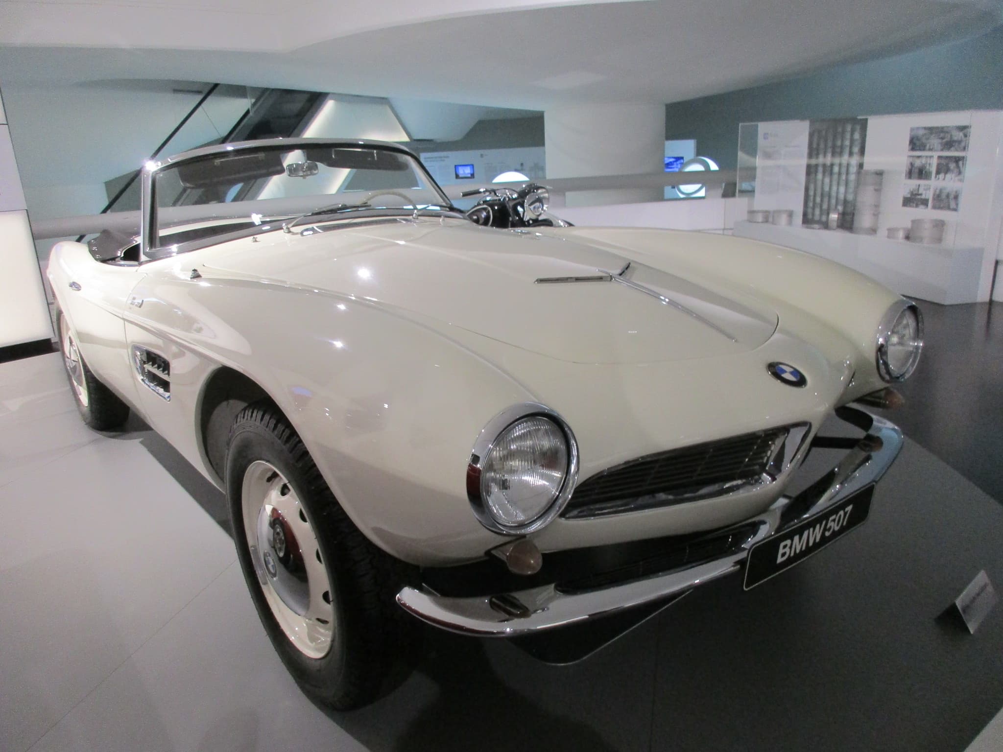 A white BMW 507 roadster in a museum, seen from the front right.